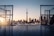 A scenic view of a city skyline with the CN Tower in the background, framed by two structures resembling hockey goals. The sunlight is casting a warm glow as it reflects off the water, creating a serene atmosphere.