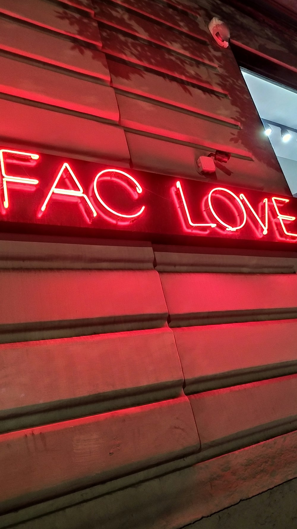 Eine Leuchtreklame mit der Aufschrift FAC Love an der Seite eines Gebäudes
