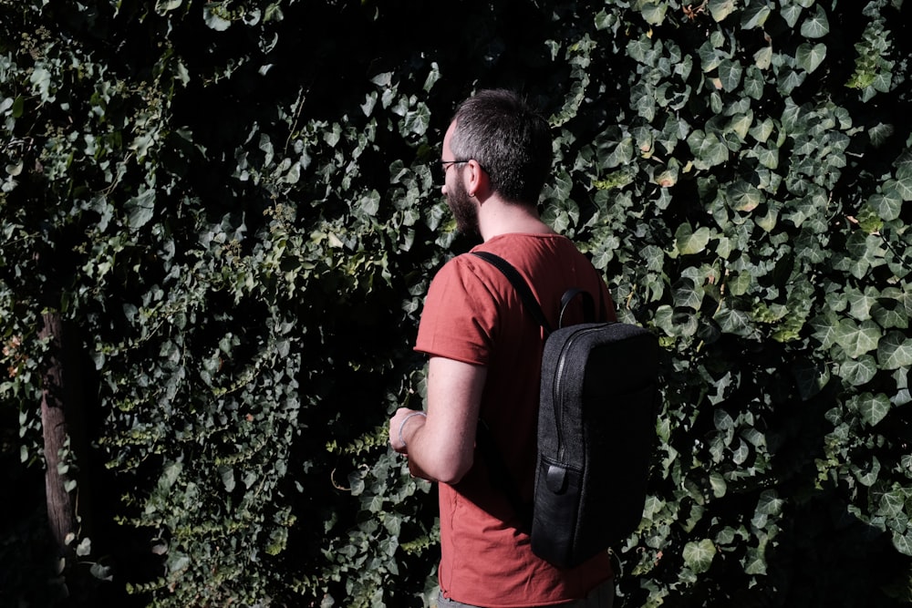 man in red shirt standing and carrying backpack