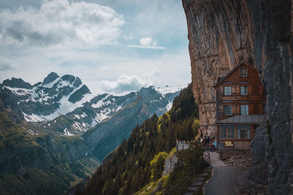 a house on a cliff with mountains in the background