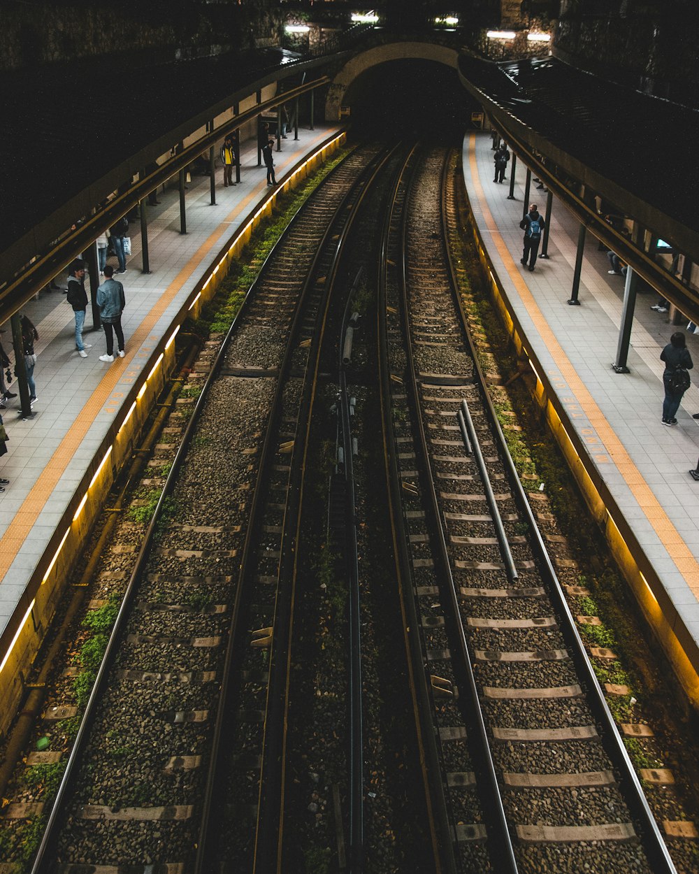 people standing beside train tracks