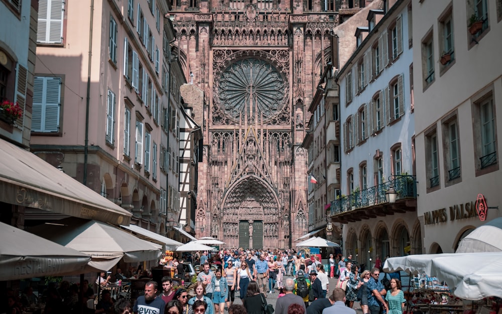 a crowd of people walking down a street next to tall buildings