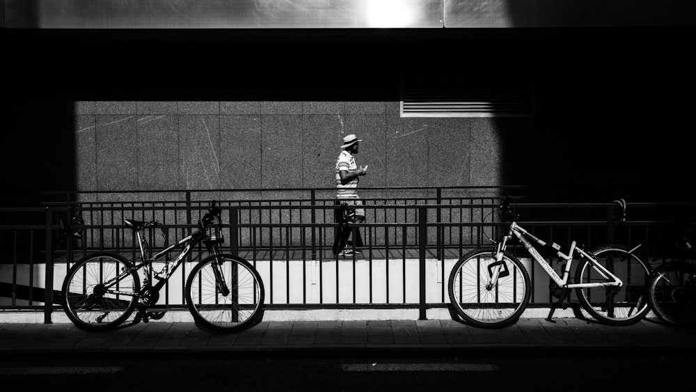 a black and white photo of a man standing next to a row of bikes