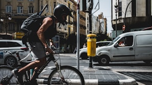 A delivery person riding a bicycle through a busy city street.