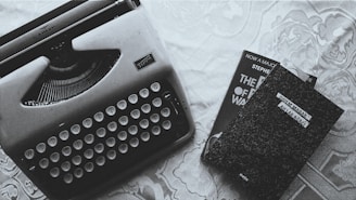 A vintage typewriter next to a stack of old books on a wooden table.
