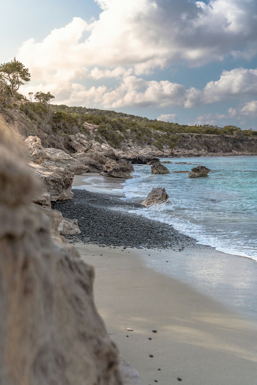 a sandy beach next to the ocean under a cloudy sky