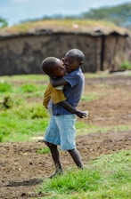 boy in grey t-shirt holding child at open field