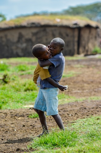 boy in grey t-shirt holding child at open field