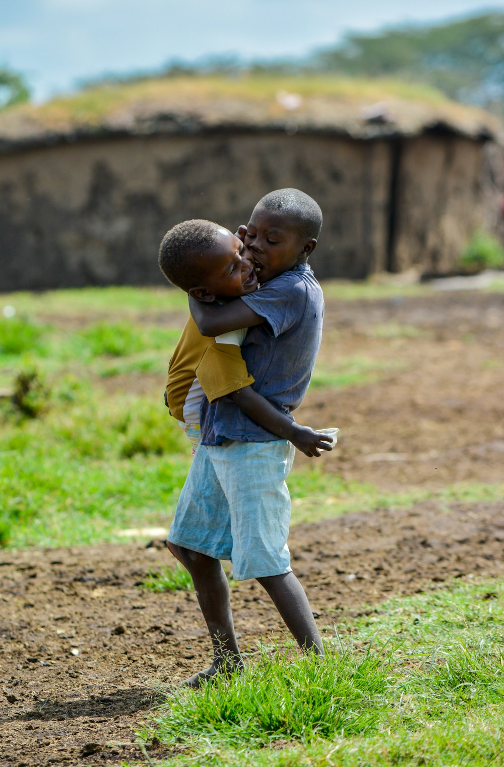 boy in grey t-shirt holding child at open field