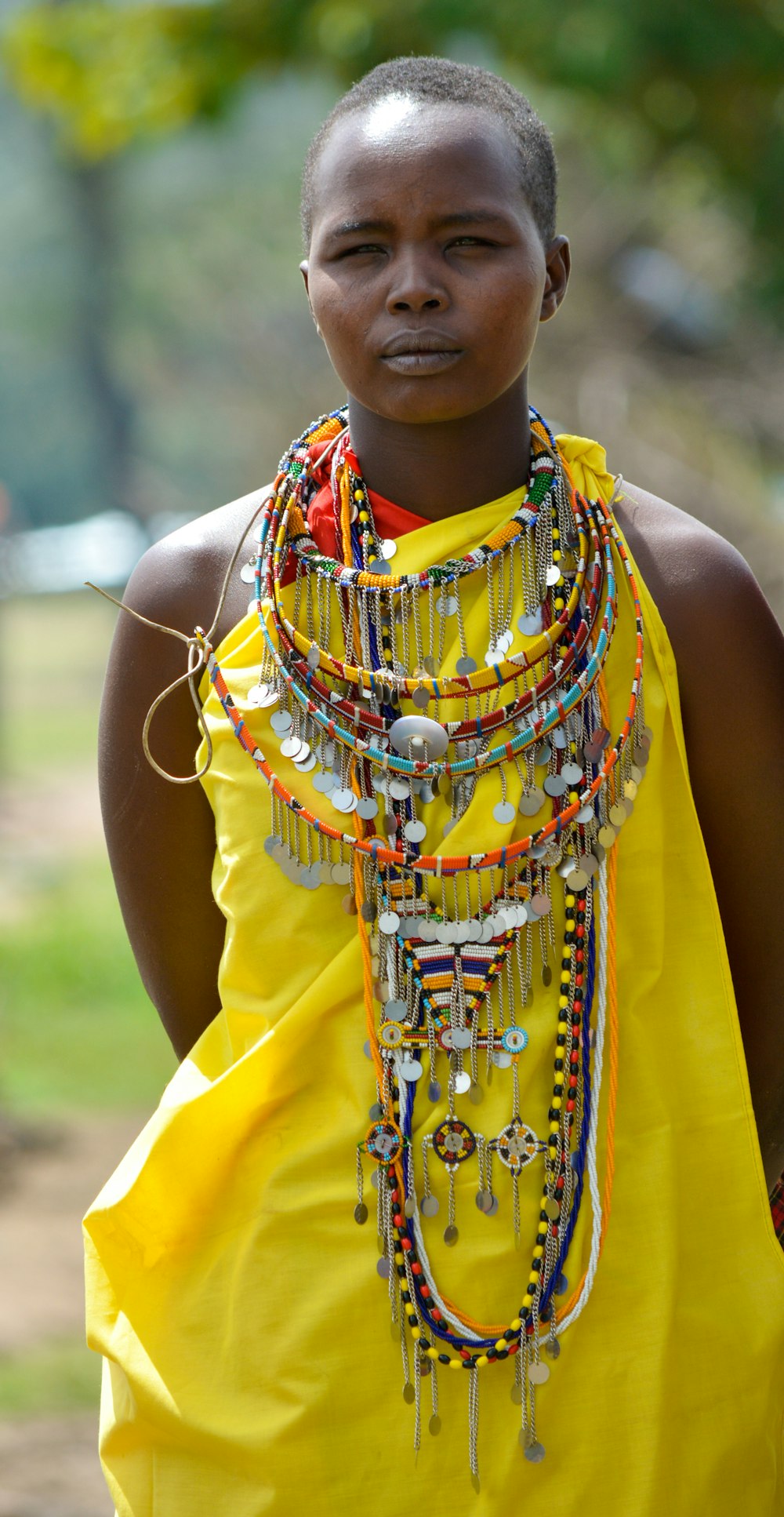 a woman in a yellow dress with a bunch of necklaces on her neck