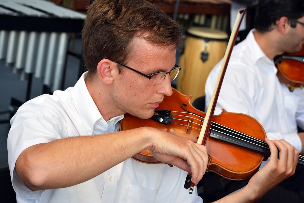 a man playing a violin in front of other men