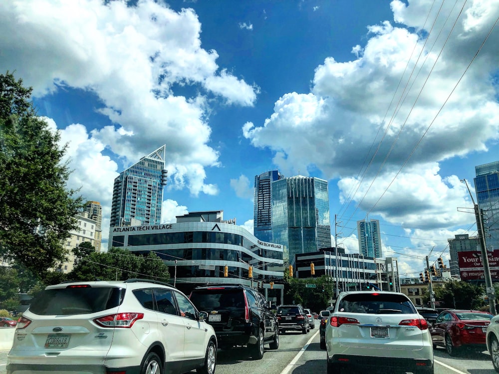 different vehicles on road viewing city with high-rise buildings under white and blue skies