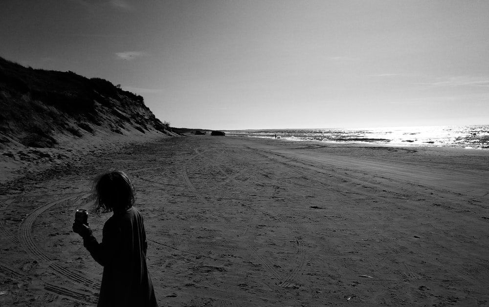 Photographie en niveaux de gris d’une femme sur la plage