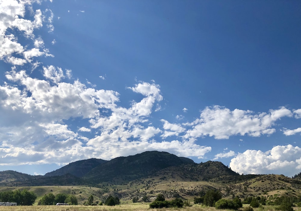 mountain under white clouds and blue sky during daytime