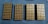 Four rectangular trays filled with neatly arranged brass-colored bullets are placed on a blue textured surface.