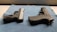 Two handguns are positioned on a blue textured mat, one with a black and silver color scheme and the other entirely black. The surface they are on appears to be well-lit, highlighting the details and textures of the firearms.