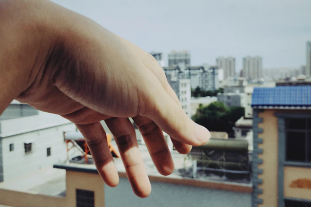 Close-up of hands exchanging property documents with a cityscape background.