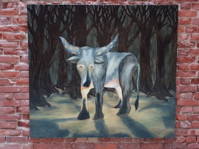 A surreal painting depicts a creature resembling an ox or bull with exaggerated features, standing on a path lighted by moonlight. The surrounding environment is a dark, dense forest with tall, shadowy trees. The creature's eyes are large and hollow, contributing to an eerie atmosphere.