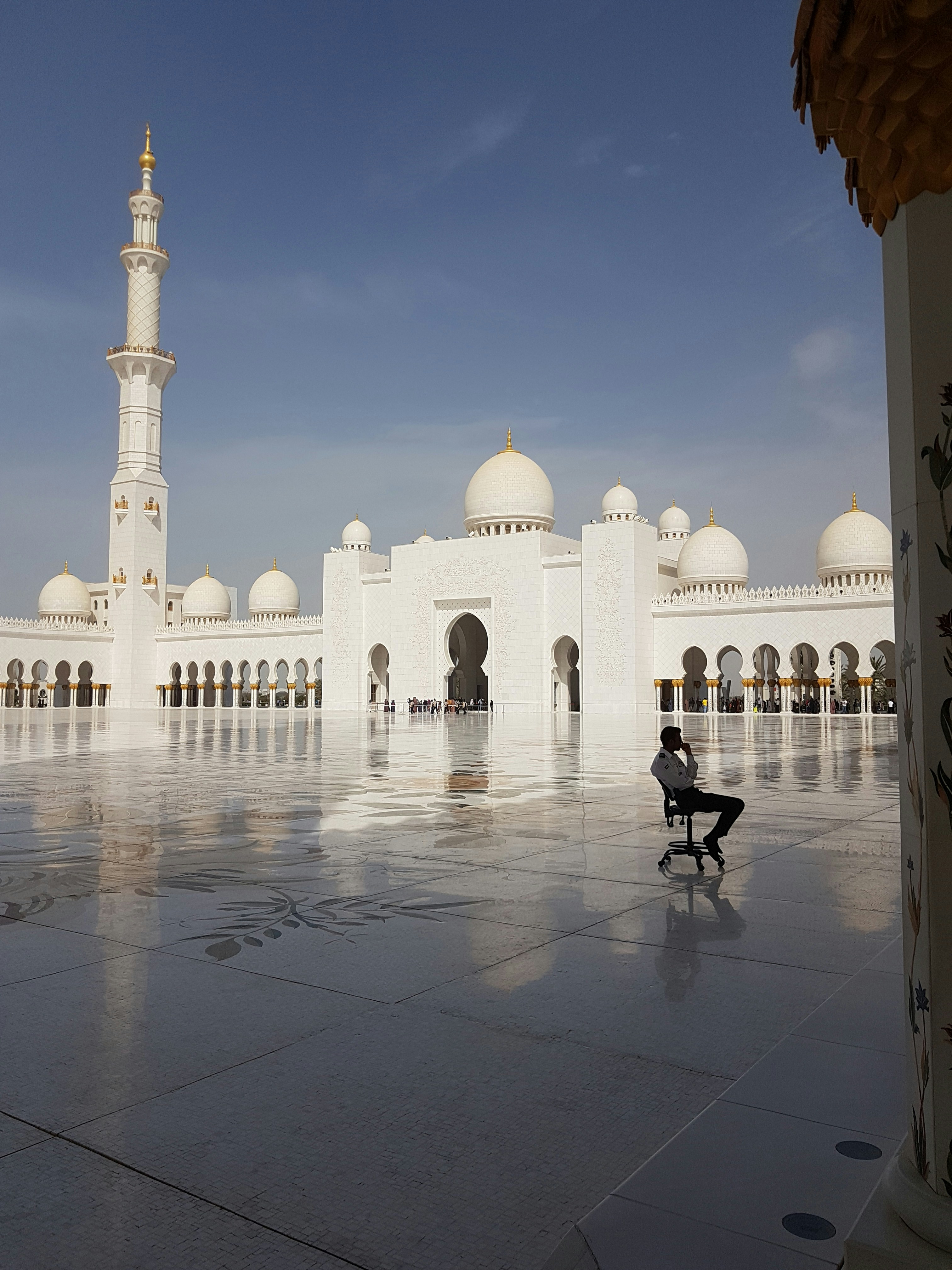 A person sitting on a chair in front of a building photo – Free ...