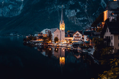 Nighttime view of the village lit up with warm glowing lights reflecting on Lake Reschen.