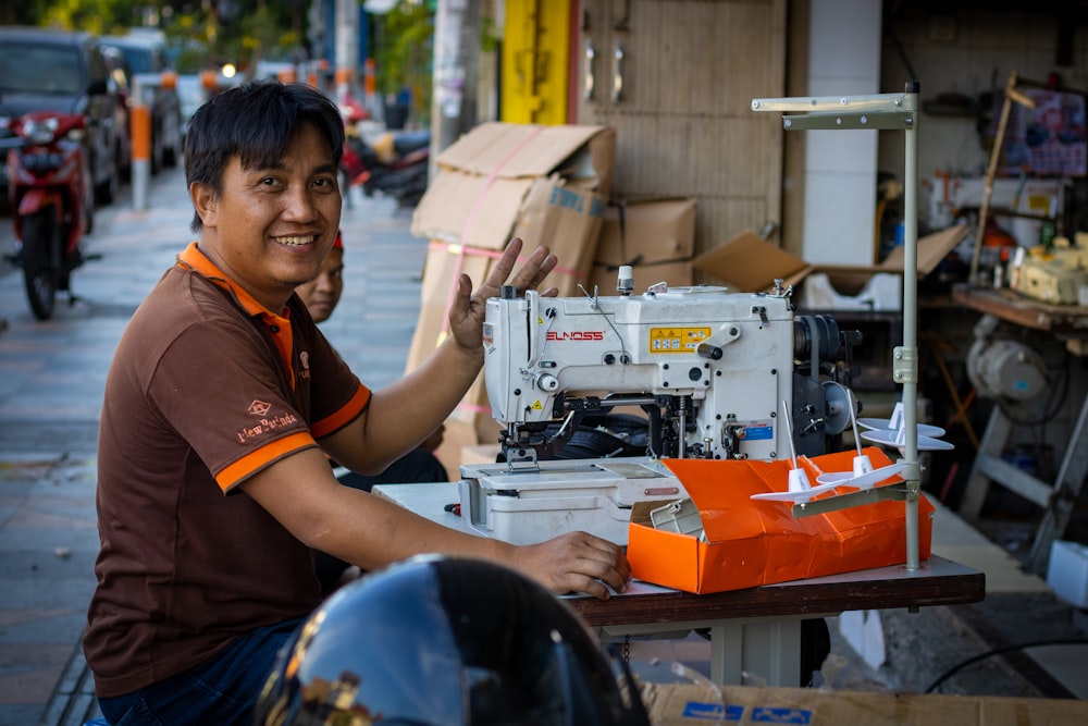 Hombre sonriente sentado al lado de la máquina de coser