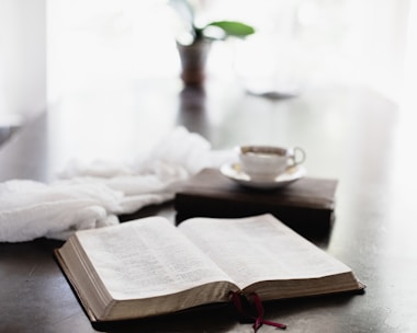 A close-up of an open e-book on a wooden table with a coffee cup.