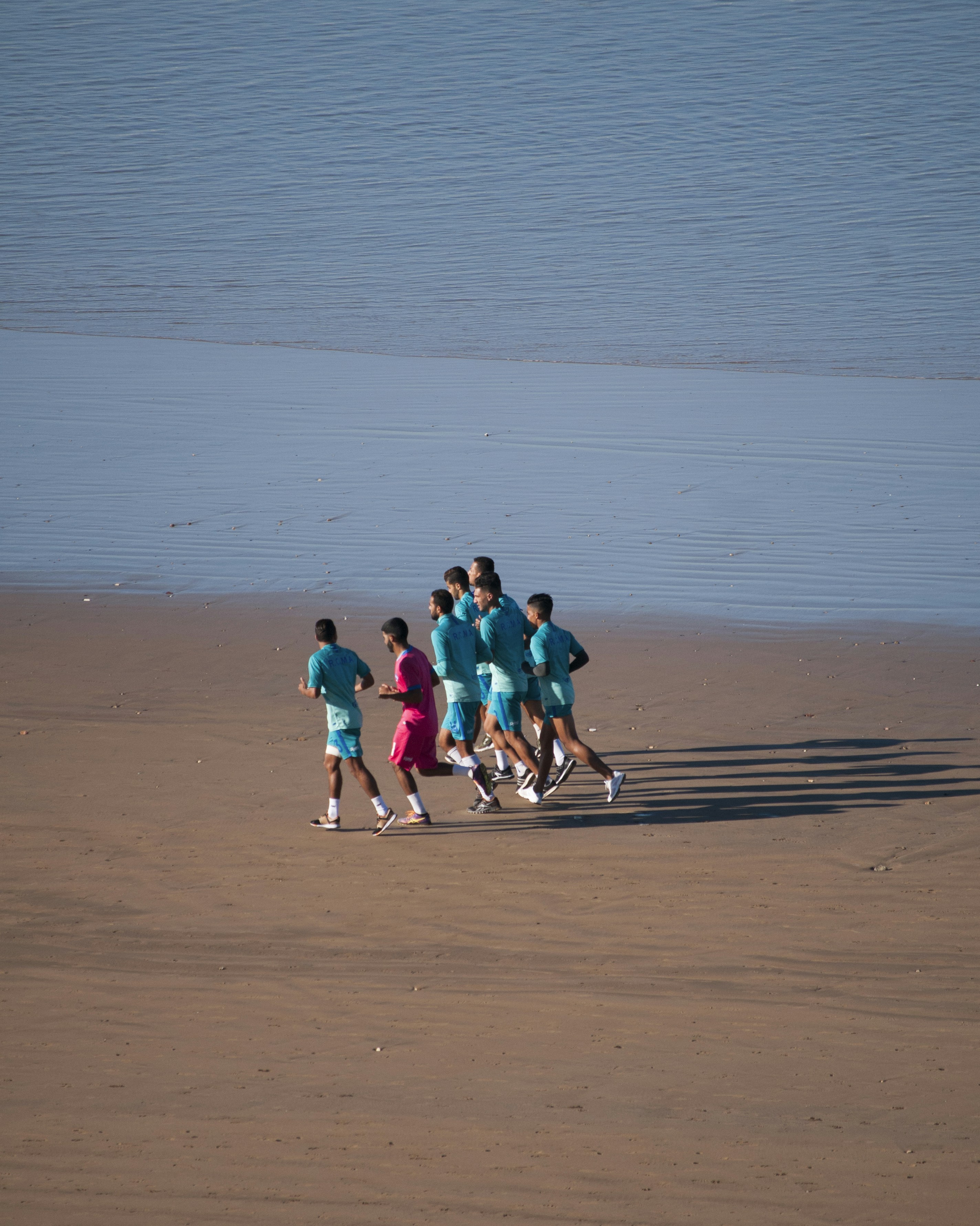 a group of people running on a beach