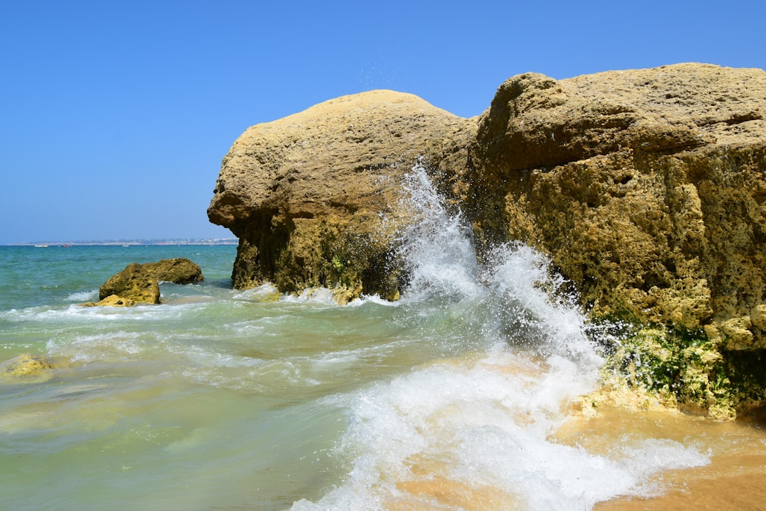 brown rock formation beside body of water at daytime, Waves against the rocks