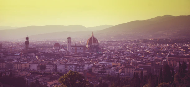 A warm sunset view of Milan’s Duomo cathedral with people admiring the rooftop.