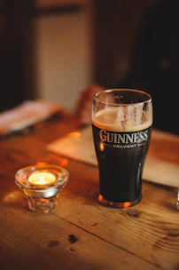 A frosty pint of Guinness with creamy head glowing under warm pub lighting.