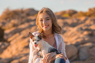 A smiling woman playing with her dog in a sunny park.