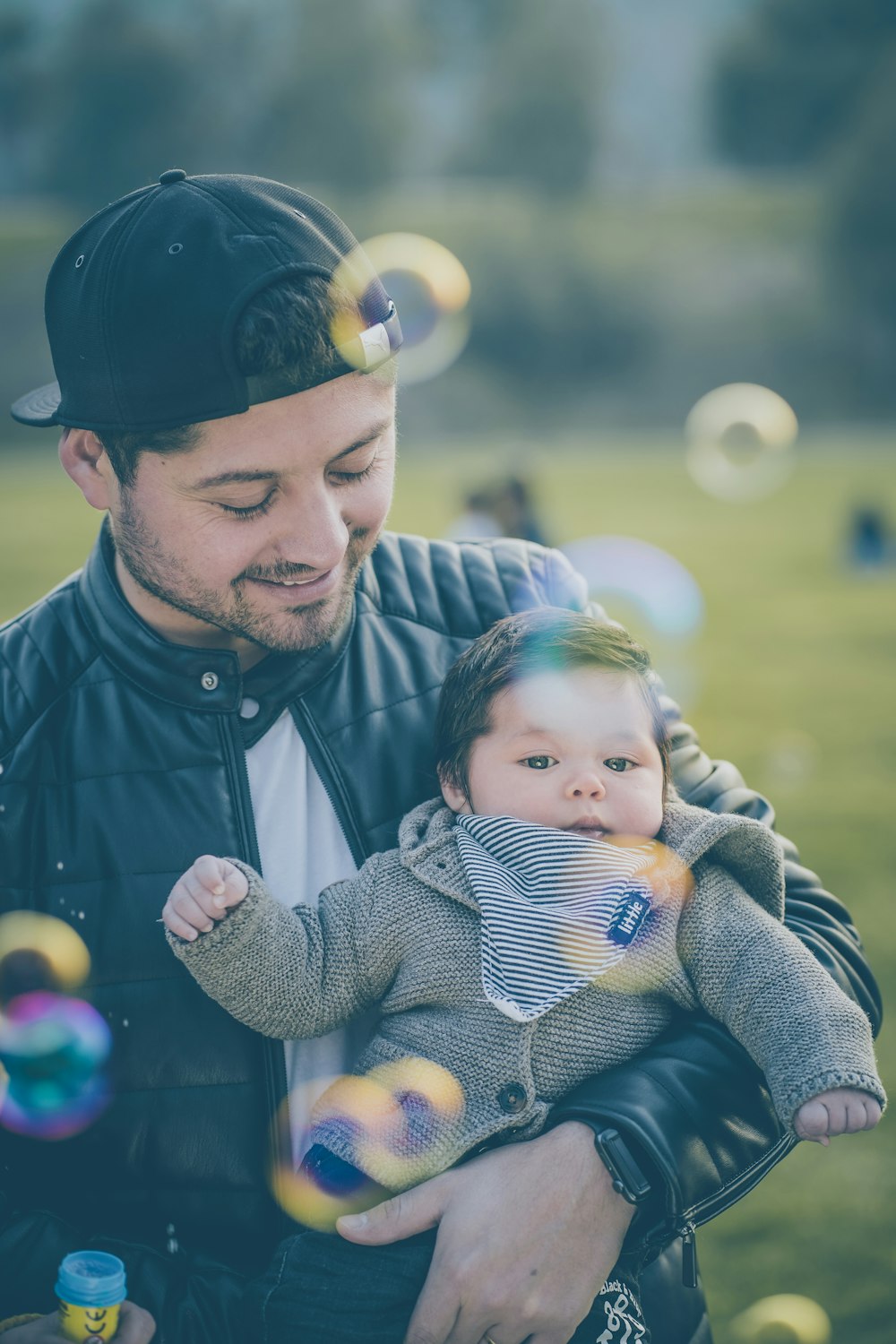 man wearing black jacket carrying baby