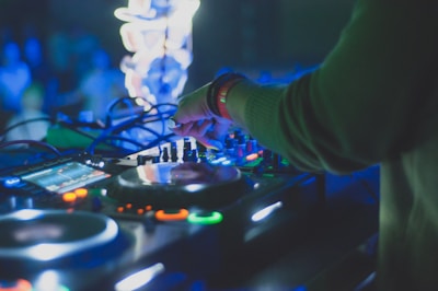 DJ mixing tracks with hands on the console, surrounded by vibrant stage lights