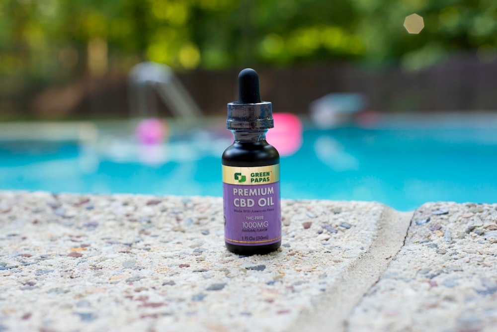 purple labeled bottle near pool during daytime