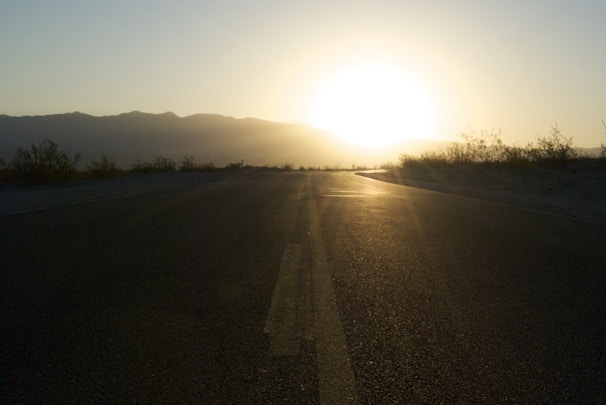 A stunning sunset over an open highway, casting a warm glow on the asphalt.
