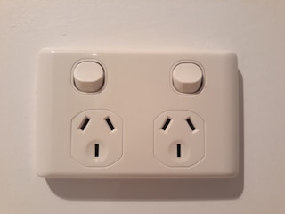 Electrician replacing outlets and switches in an office setting.