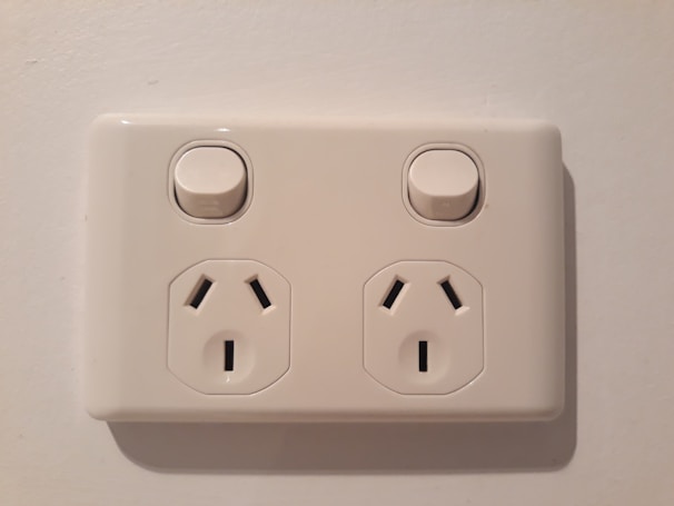 An electrician testing electrical outlets in a bright, newly renovated kitchen.