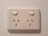 An electrical wall socket with two outlets and individual power switches, set against a light-colored wall.