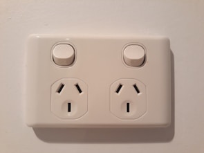 Neatly installed electrical outlets and switches on a white wall with blue accents.