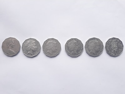 Six silver coins are lined up horizontally against a plain white background. Each coin features a profile portrait on one side, indicating heads side, and belongs to different years.