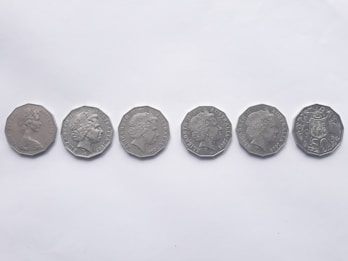 Six silver coins are lined up horizontally against a plain white background. Each coin features a profile portrait on one side, indicating heads side, and belongs to different years.