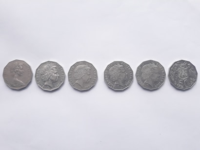 Six silver coins are lined up horizontally against a plain white background. Each coin features a profile portrait on one side, indicating heads side, and belongs to different years.