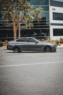 A sleek used sedan parked in front of a modern building under soft afternoon light