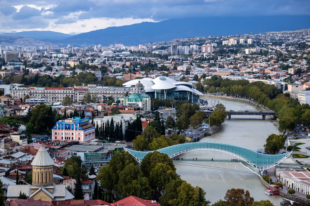 aerial photography of buildings, Tbilisi is a city of contrasts: a meeting point between eastern and western civilisations for centuries, it remains one today. Built along the riverbank of the Kura (Mtkvari, in Georgian) and surrounded by hills, Tbilisi has been settled since before the 4th century, but boasts a skyscape that includes twenty - first century architecture. Tbilisi can be international, cosmopolitan and sophisticated, yet it is essentially and distinctly Georgian and retains a close focus on local tradition and culture.