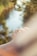 A close-up of a hand wearing a beautiful gemstone ring surrounded by natural greenery.