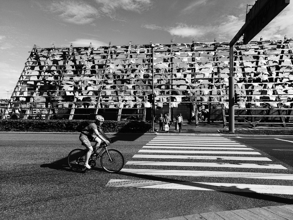 grayscale photo of man riding bike