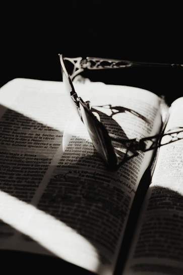 A close-up of a stylish reading glass resting on an open book with soft natural light.