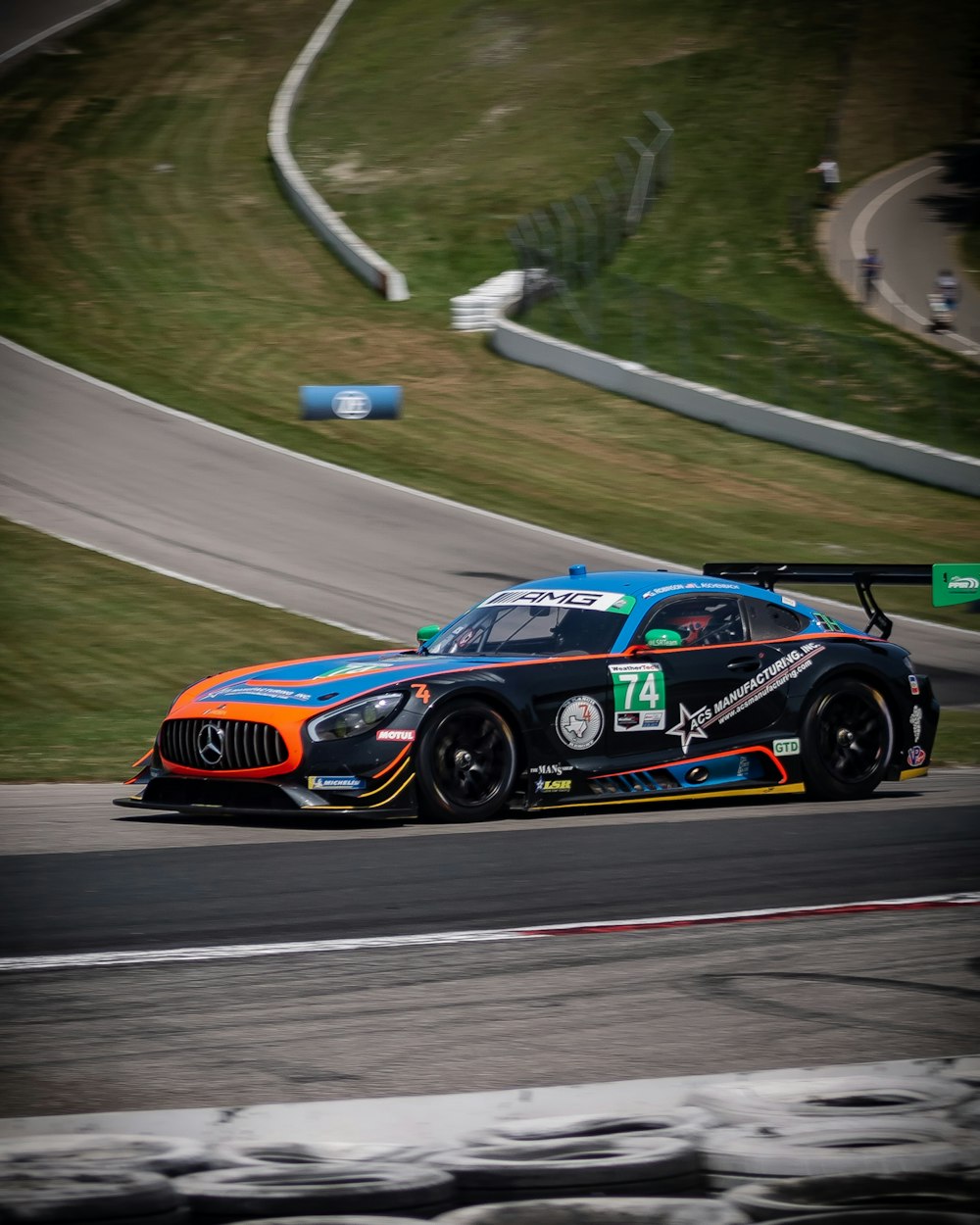 black, blue, and orange Mercedes-Benz race car on road