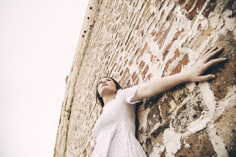 woman wearing white dress leaning on wall