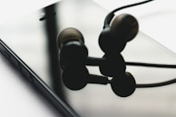 Close-up of a hand scanning a Sync Tag on a pair of headphones with a smartphone, showing instant connection.